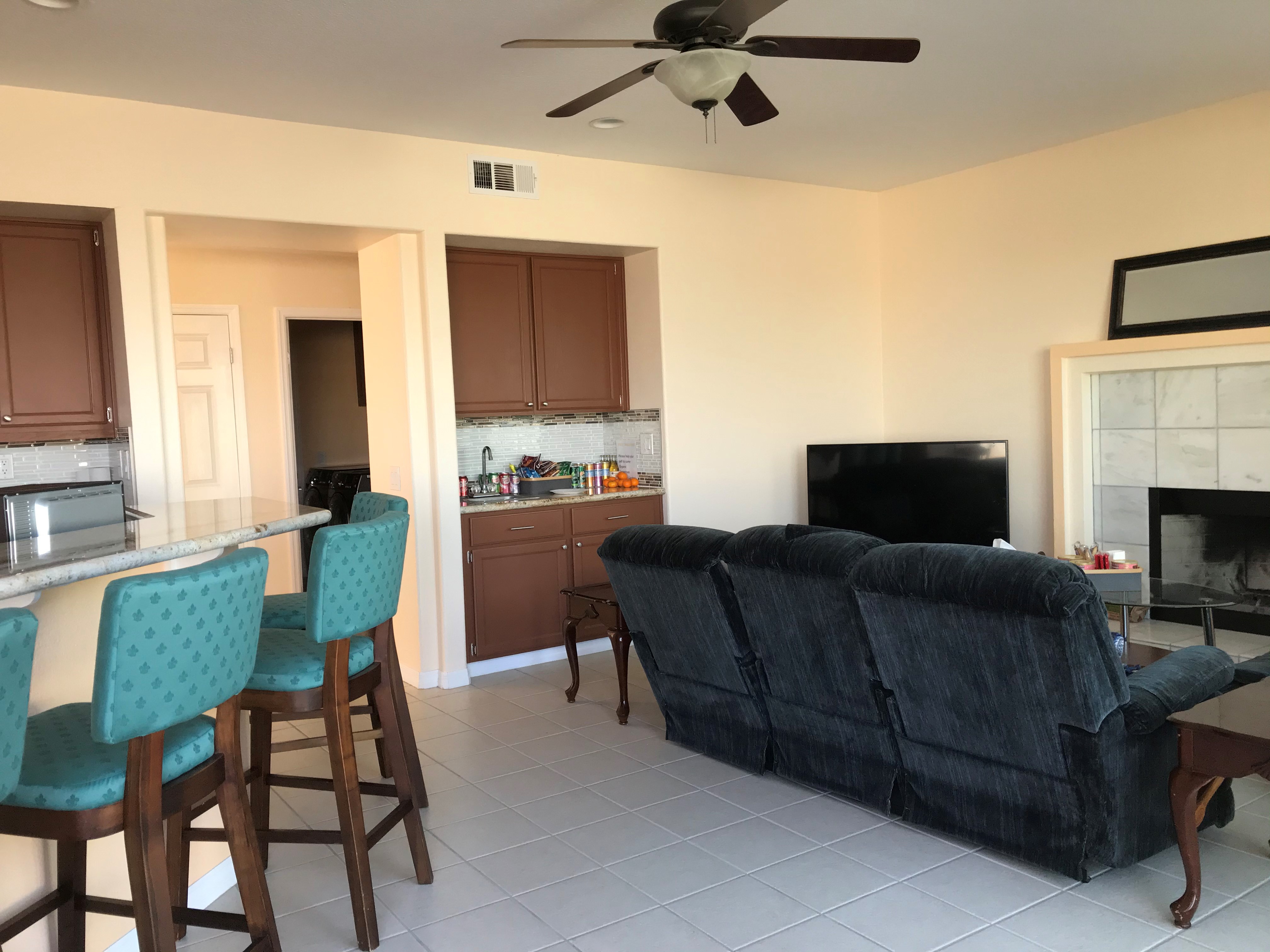 Family room with large TV, fireplace, reclining sofa, and second sink/wet bar area