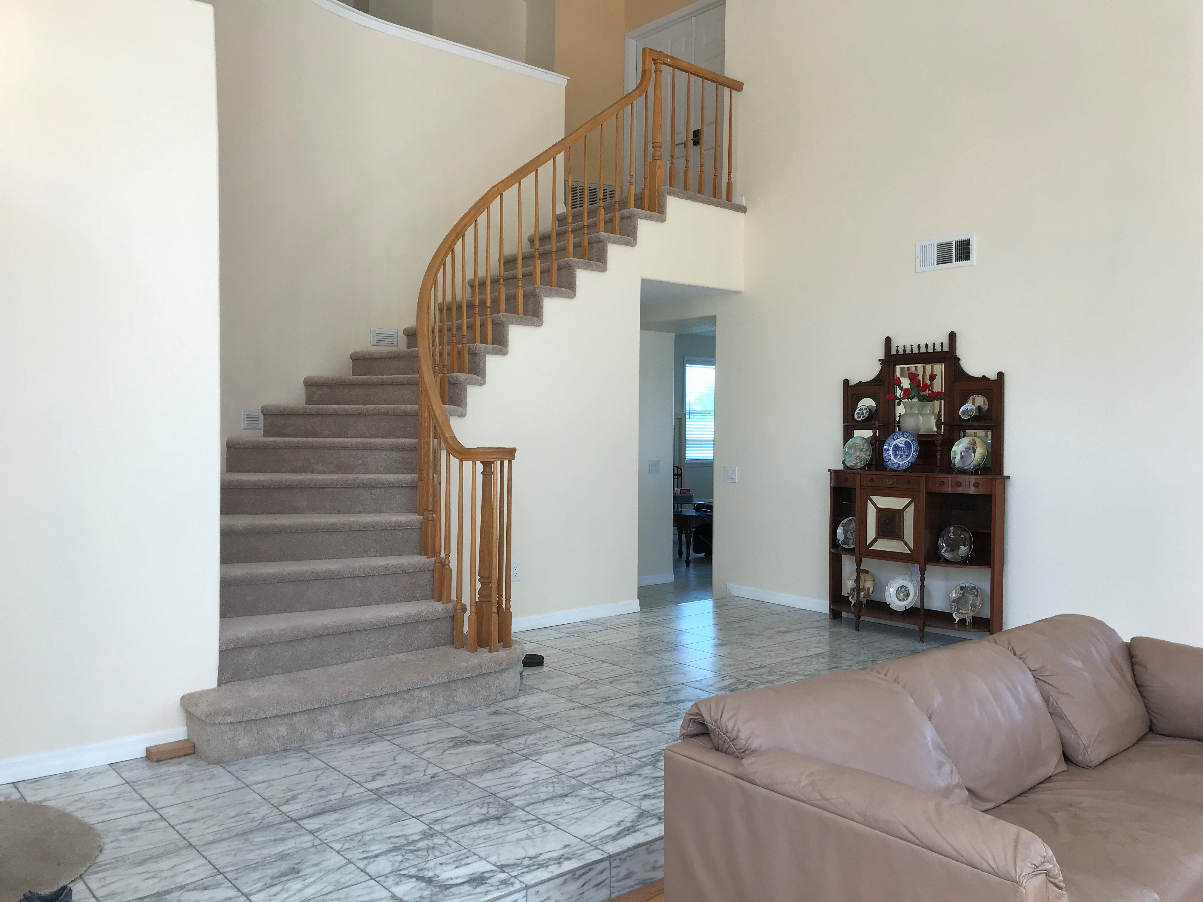 Grand curved staircase and soaring double-height foyer with marble tile floors