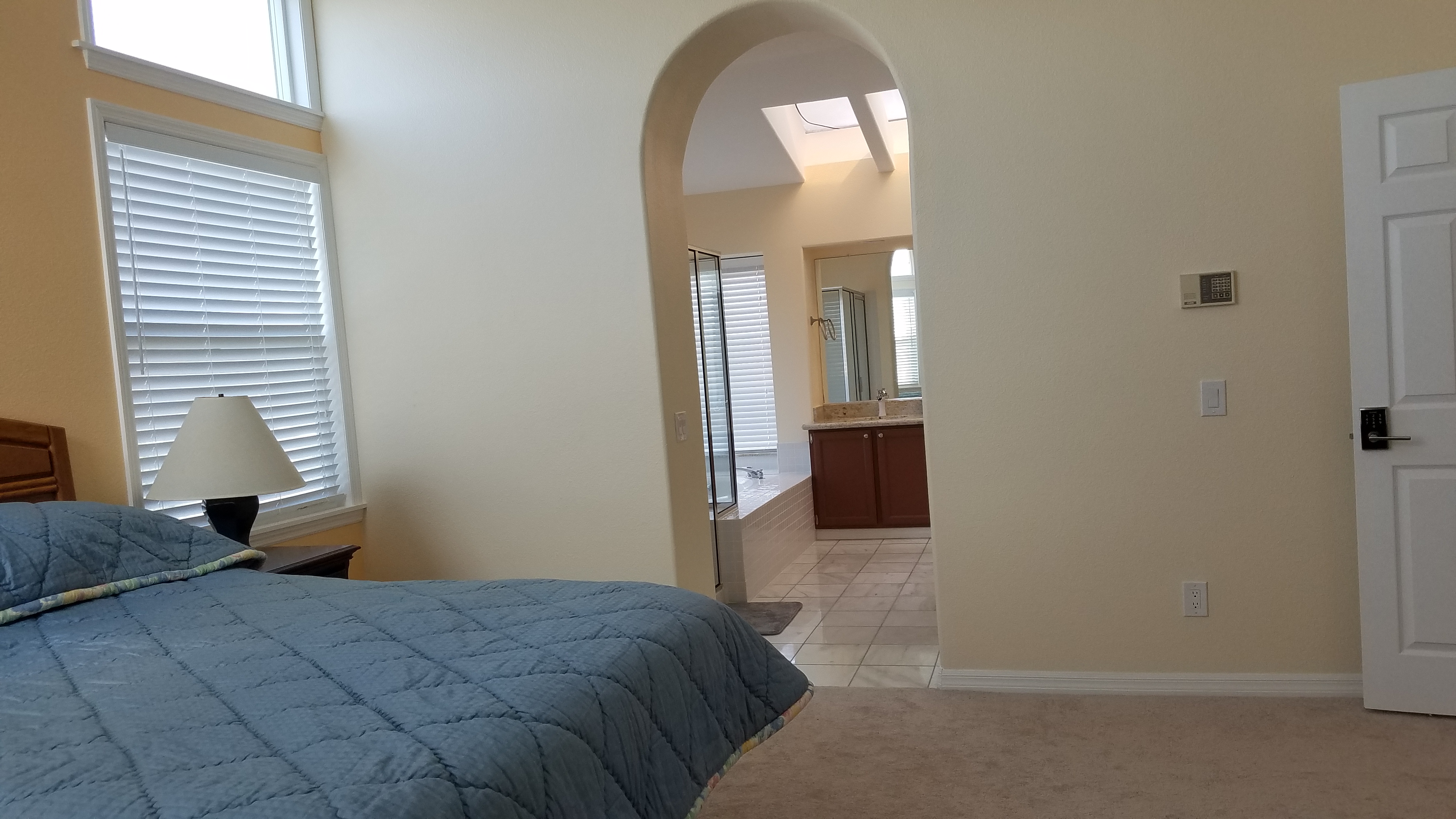 Spacious master bedroom with vaulted ceilings and solid blue bedding