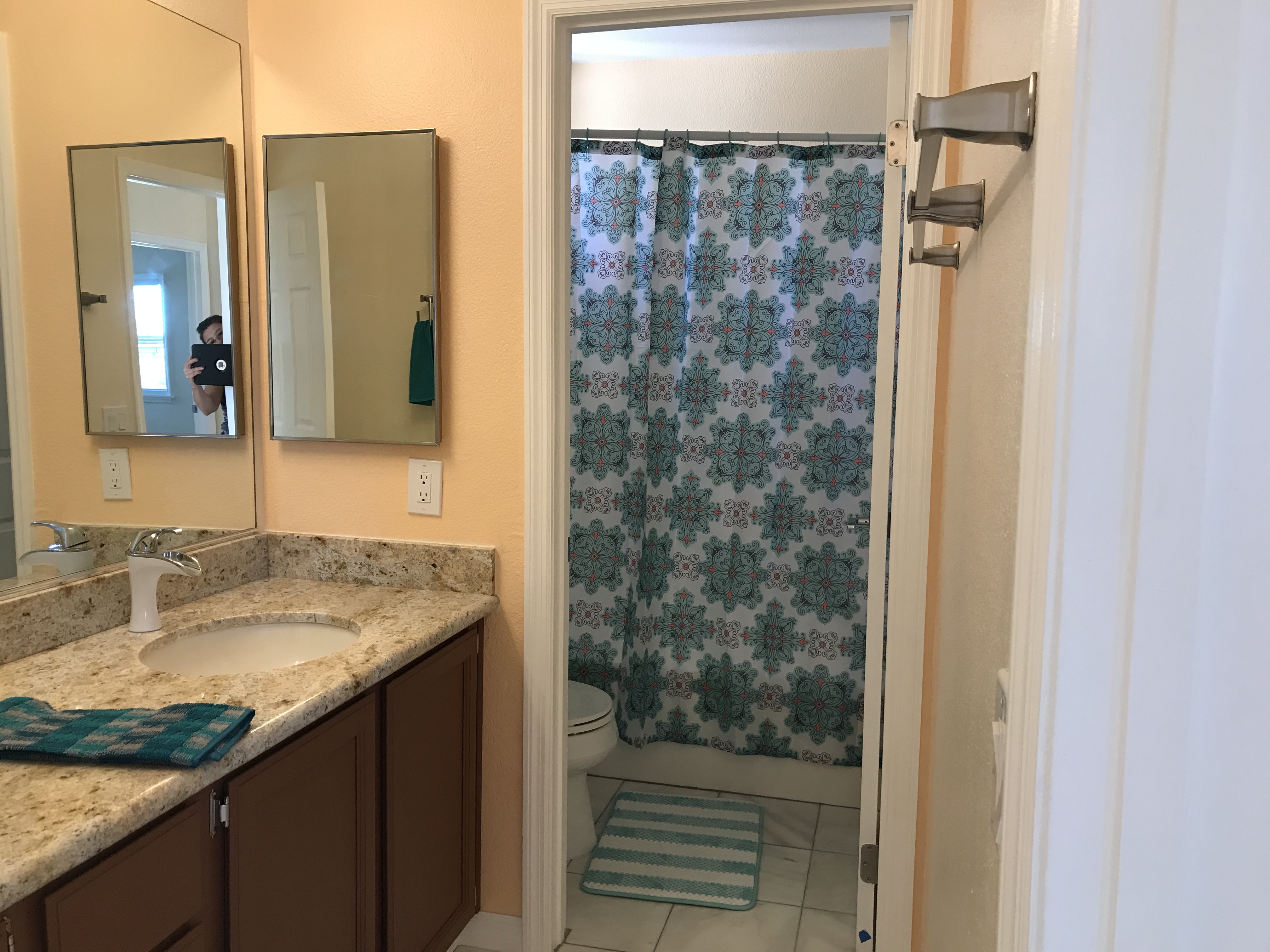 Upstairs bathroom with granite vanity, modern faucet, and separate shower compartment with patterned curtain