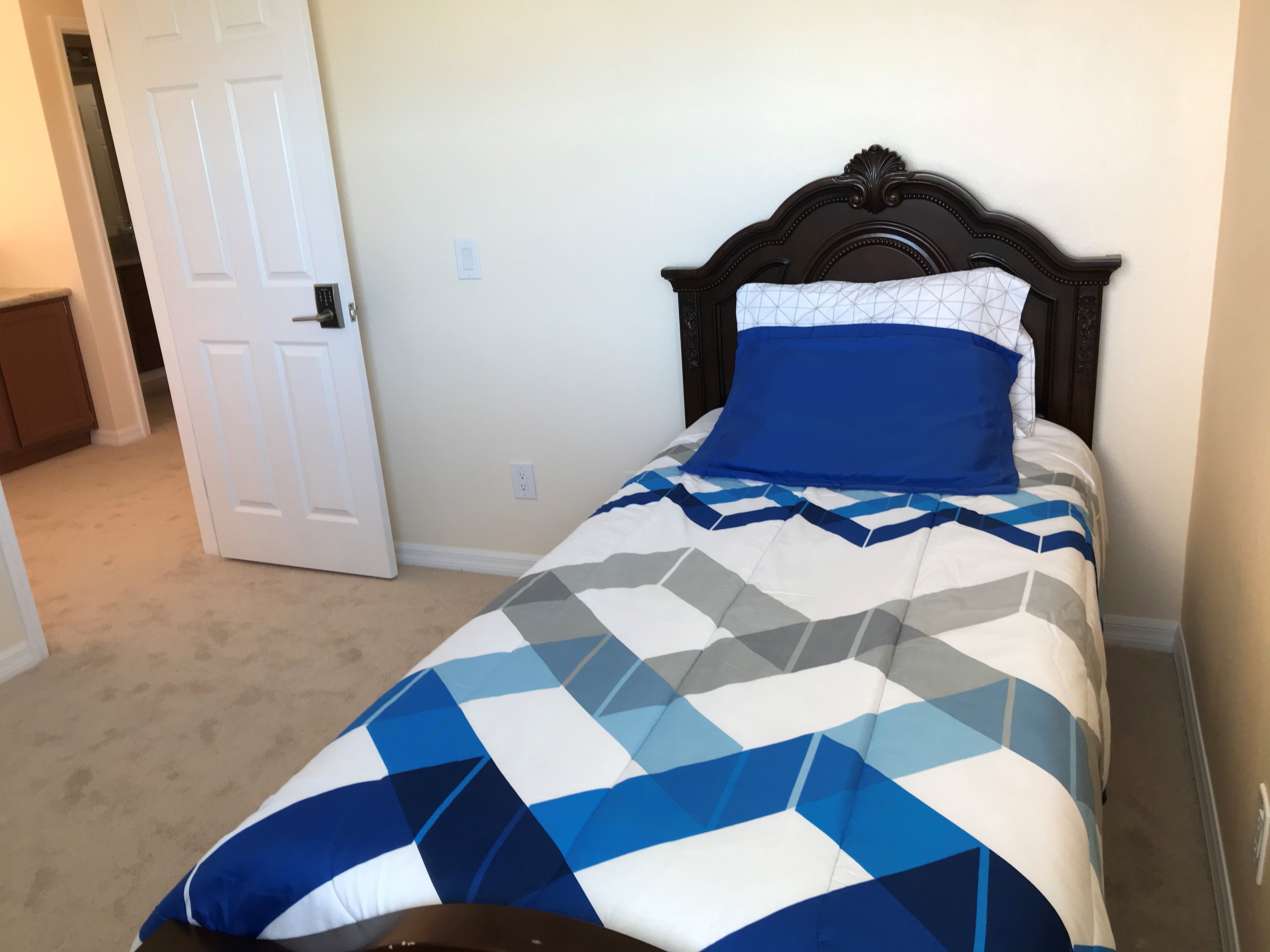 Furnished upstairs bedroom B with twin bed, floral bedding, dresser, and bright window